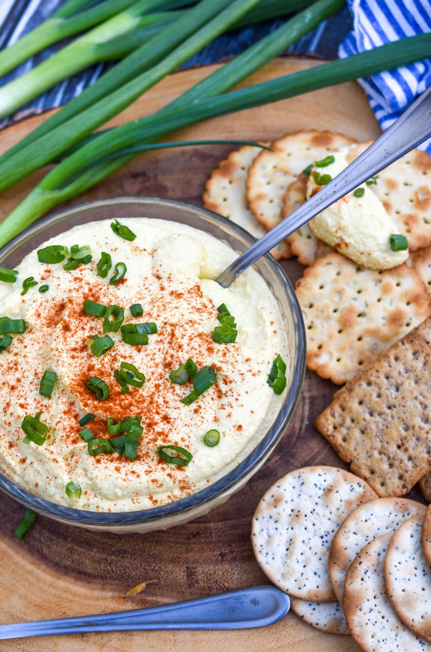 DEVILED EGG DIP TOPPED WITH SLICED GREEN ONIONS IN A SMALL GLASS BOWL