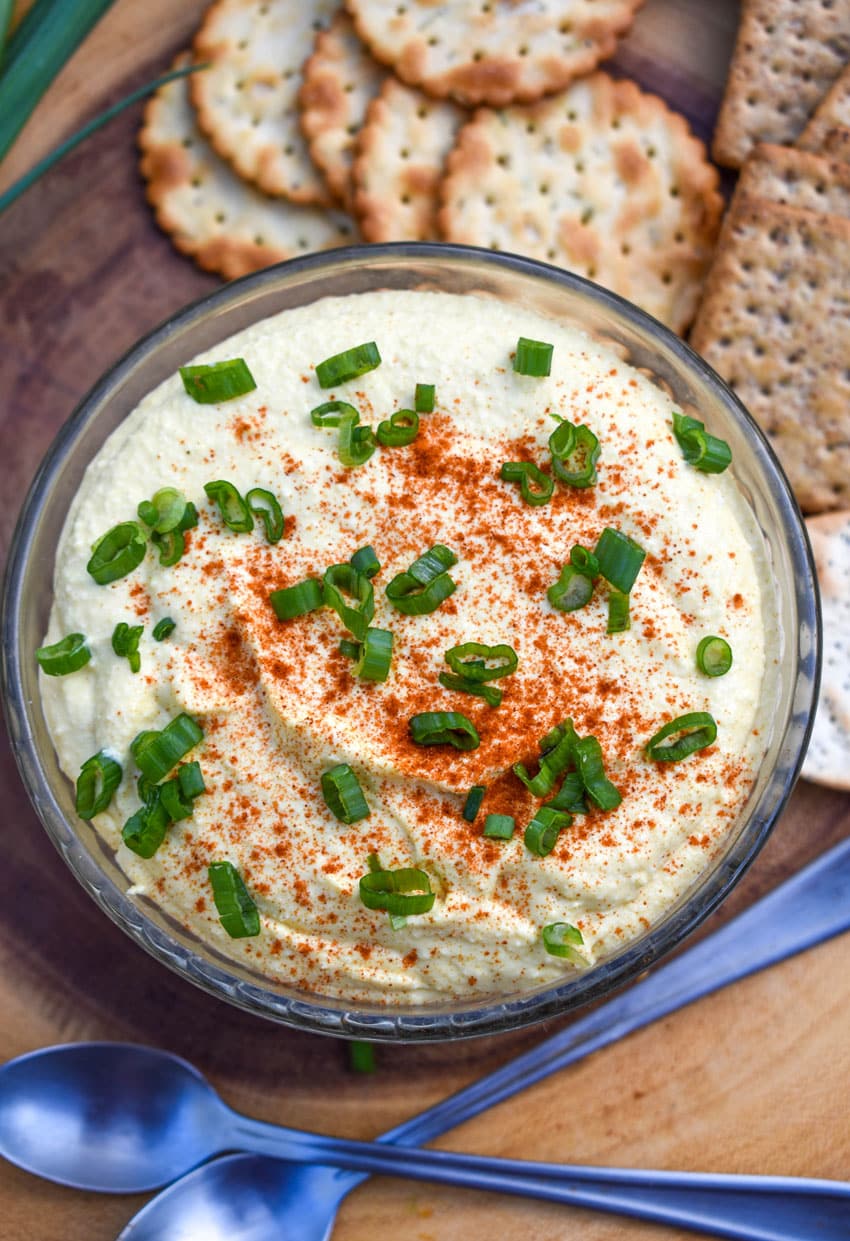 DEVILED EGG DIP TOPPED WITH SLICED GREEN ONIONS IN A SMALL GLASS BOWL