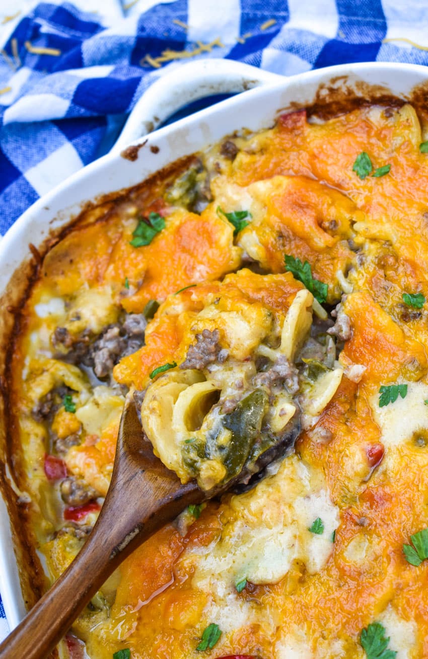 a wooden spoon scooping hobo casserole out of a white baking dish