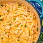 CREAMY BUFFALO CHICKEN PASTA TOPPED WITH SLICED GREEN ONIONS IN A LARGE BLUE DUTCH OVEN