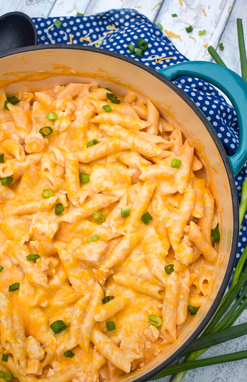 CREAMY BUFFALO CHICKEN PASTA TOPPED WITH SLICED GREEN ONIONS IN A LARGE BLUE DUTCH OVEN