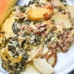 zuppa toscana casserole on a white dinner plate with a breadstick on the side