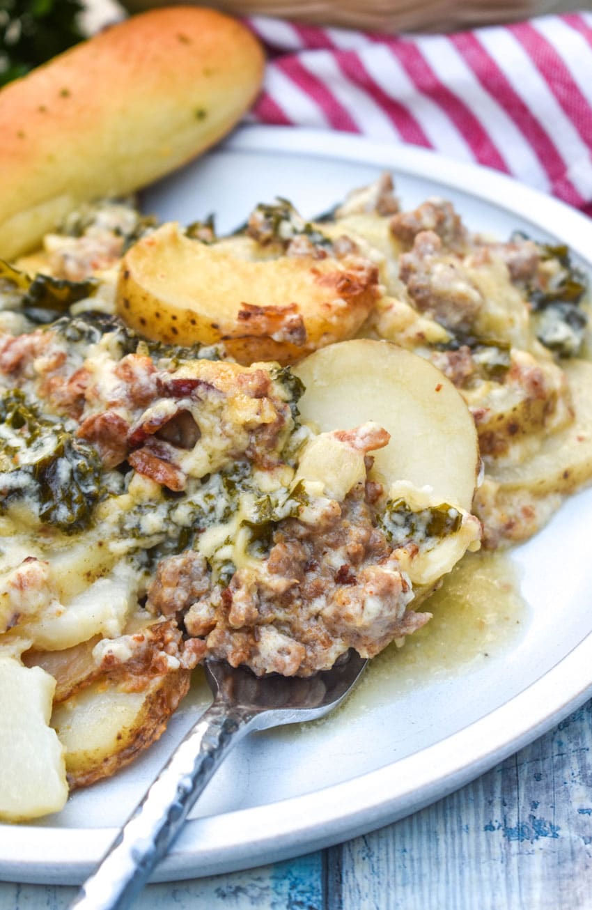 a silver fork resting on the edge of a dinner plate topped with zuppa toscana casserole