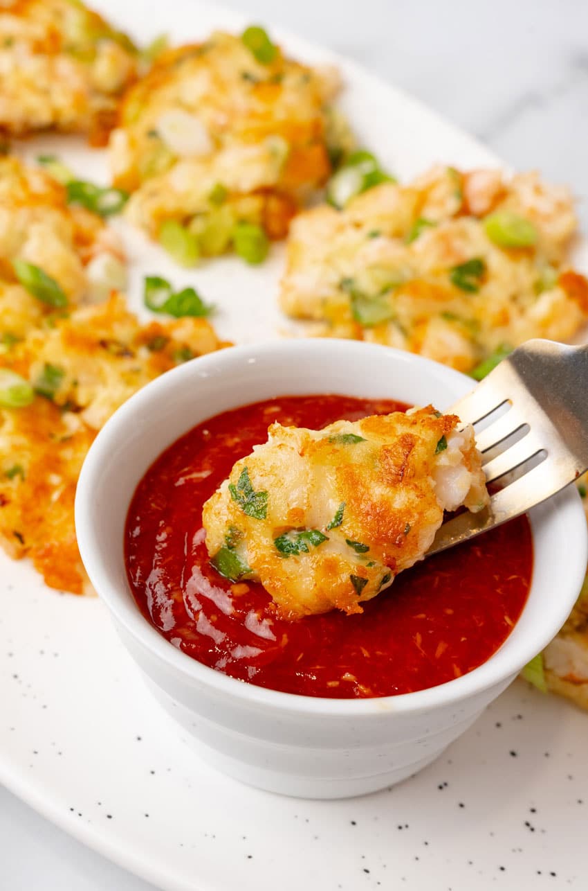 a silver fork holding up a piece of a shrimp fritter