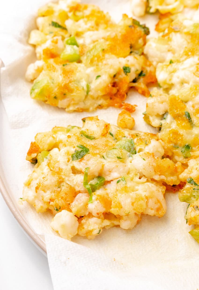 fried shrimp fritters draining on a paper towel lined plate