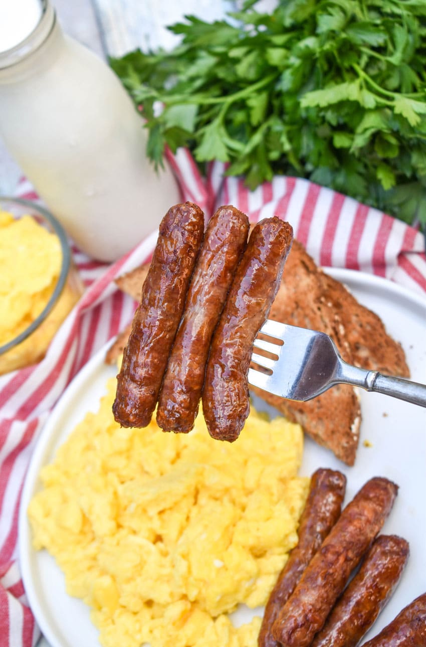 a silver fork holding up three air fried breakfast sausage links