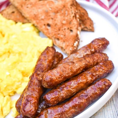 air fryer breakfast links on a white plate with scrambled eggs and toast on the side