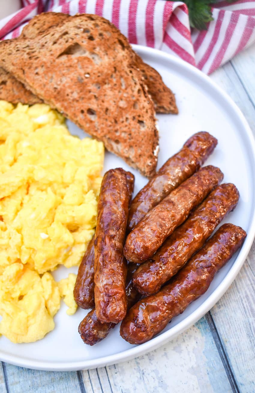 air fryer breakfast links on a white plate with scrambled eggs and toast on the side