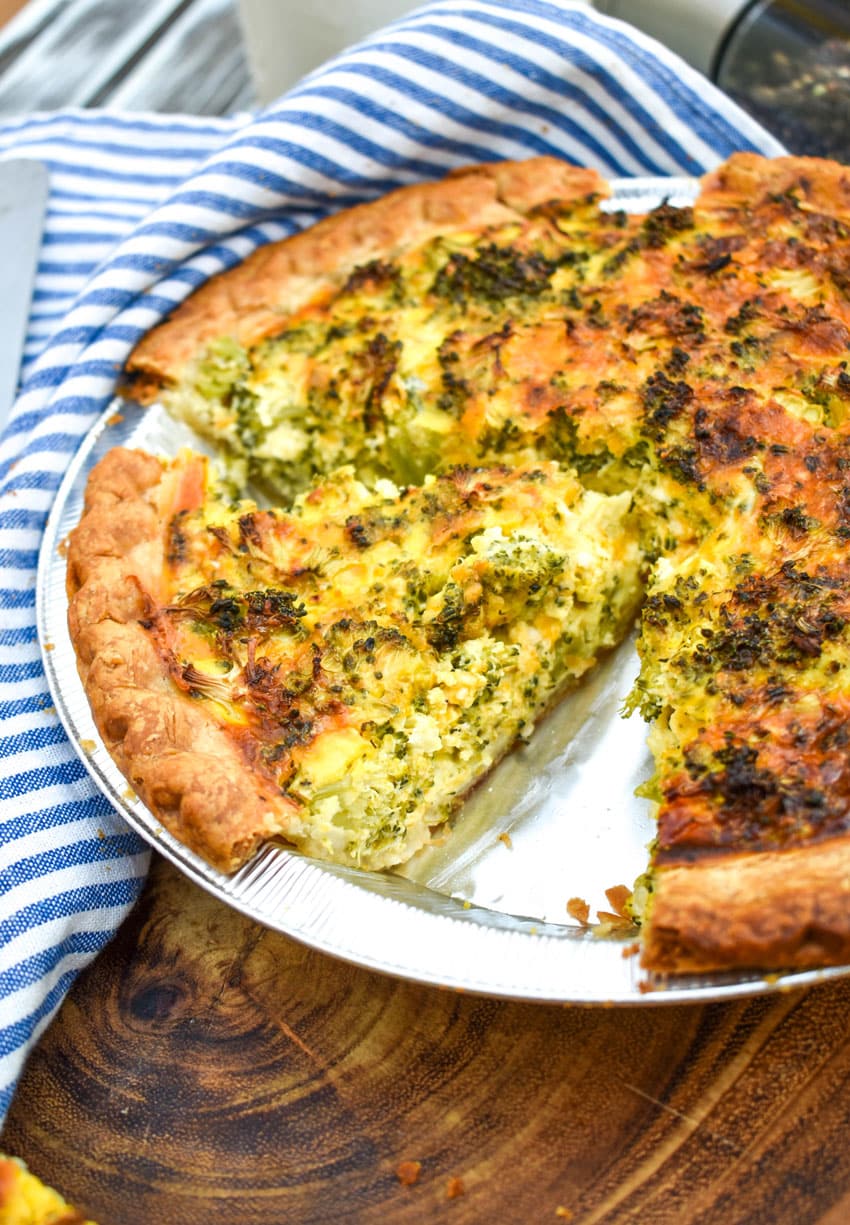 a homemade broccoli cheddar quiche on a wooden cutting board