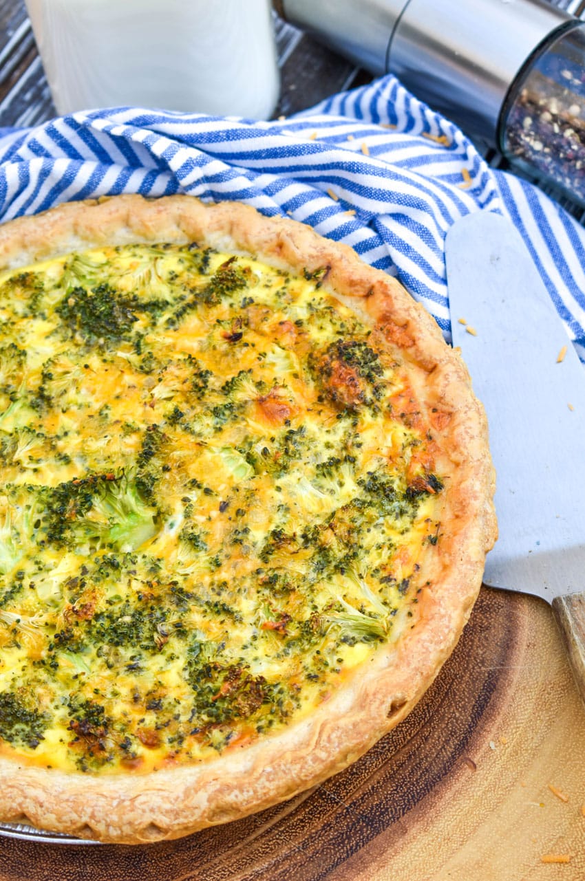 a homemade broccoli cheddar quiche on a wooden cutting board