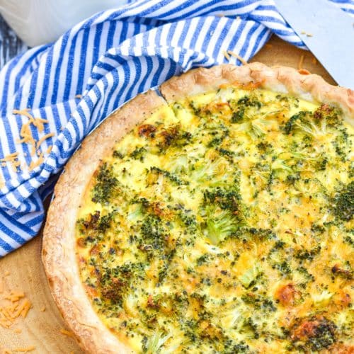 a homemade broccoli cheddar quiche on a wooden cutting board