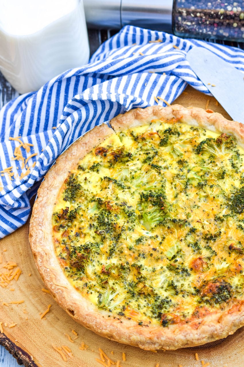 a homemade broccoli cheddar quiche on a wooden cutting board