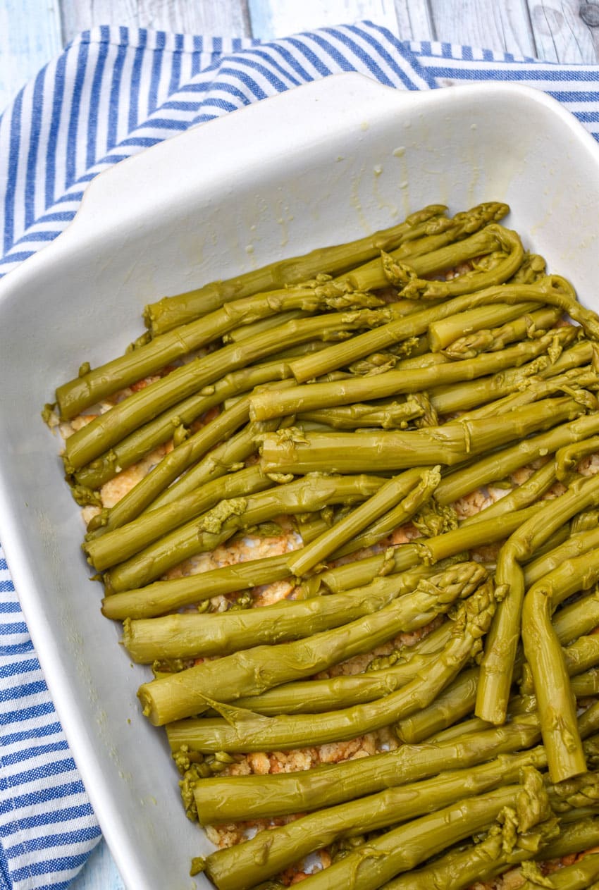 drained canned asparagus spears spread out in an even layer in a white baking dish