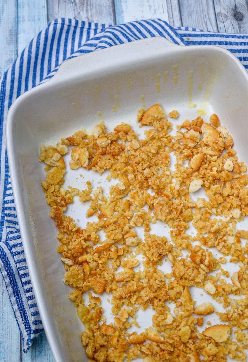 buttered cracker crumbs spread out in the bottom of a white baking dish