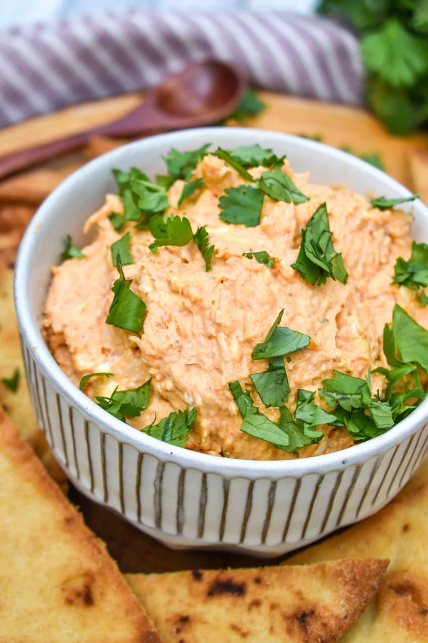 Chicken Tikka Masala Dip With Baked Naan Chips chicken tikka masala dip in a small white bowl surrounded by baked naan bread chips