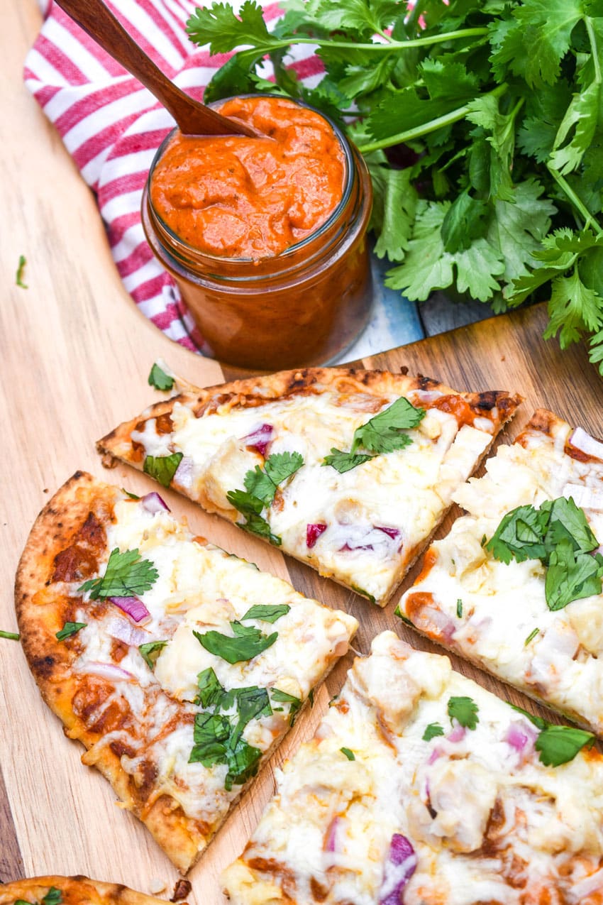 a sliced chicken tikka masala pizza on a wooden pizza peel