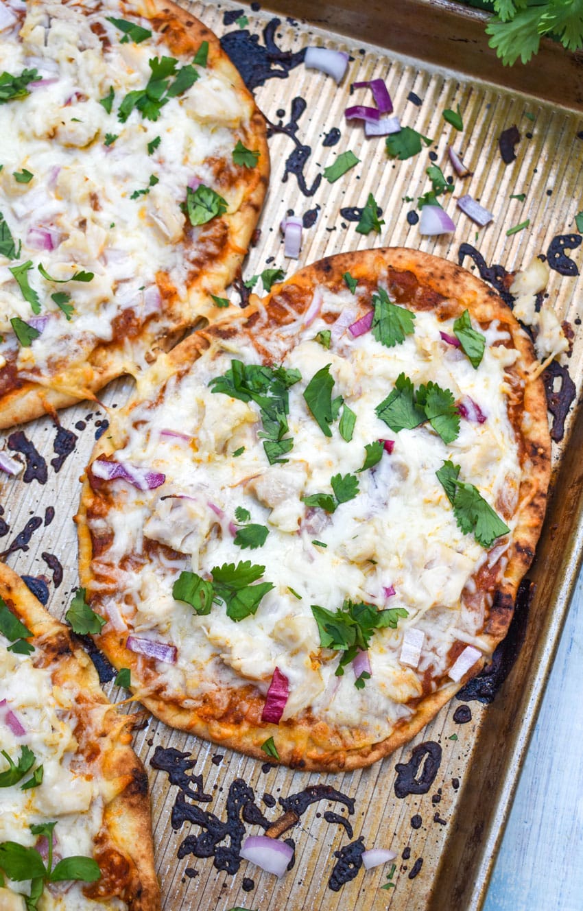 chicken tikka masala naan bread pizzas on a metal baking sheet