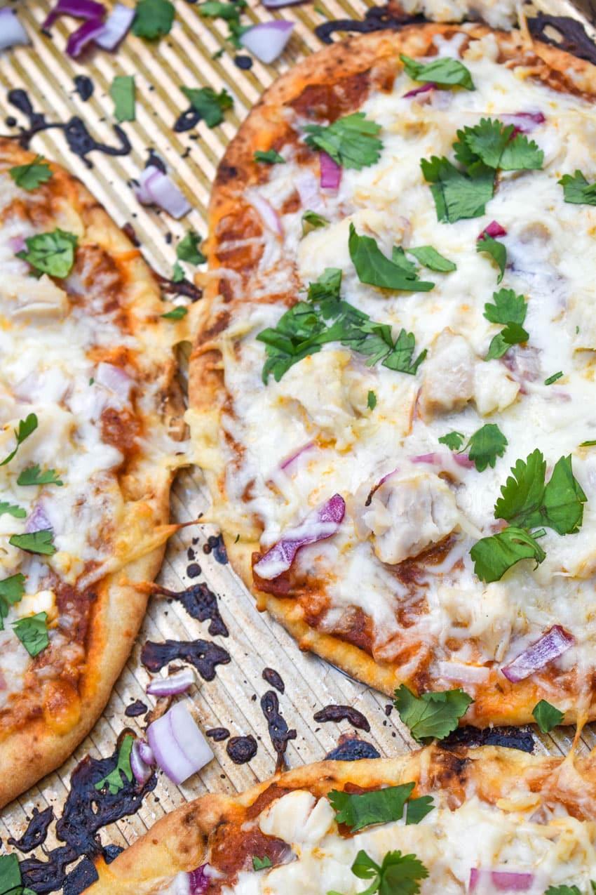 chicken tikka masala naan bread pizzas on a metal baking sheet