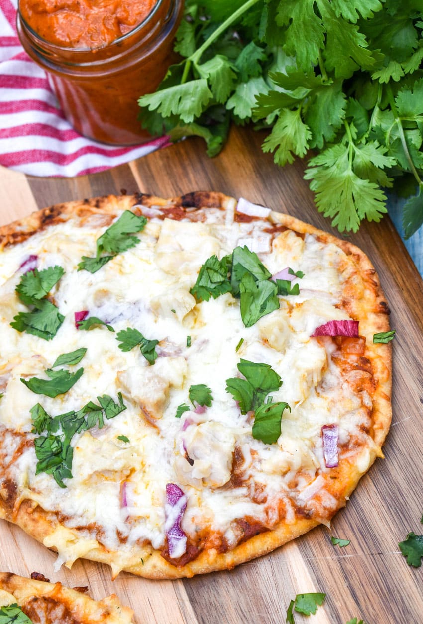 a chicken tikka masala naan bread pizza on a wooden pizza peel