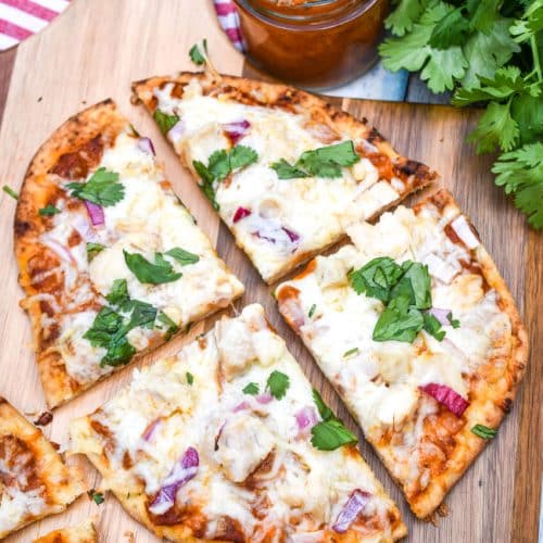 a sliced chicken tikka masala pizza on a wooden pizza peel
