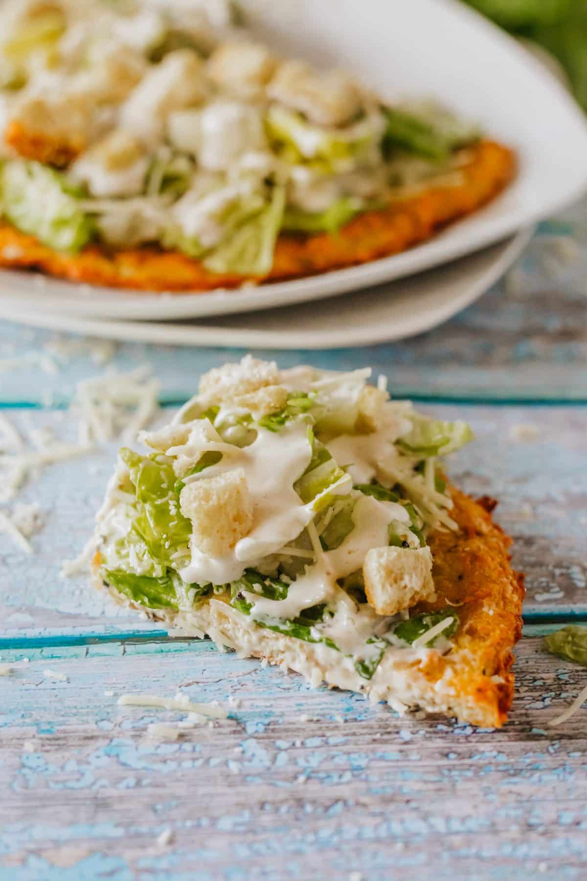 a slice of tiktok caesar chicken pizza on a wooden table