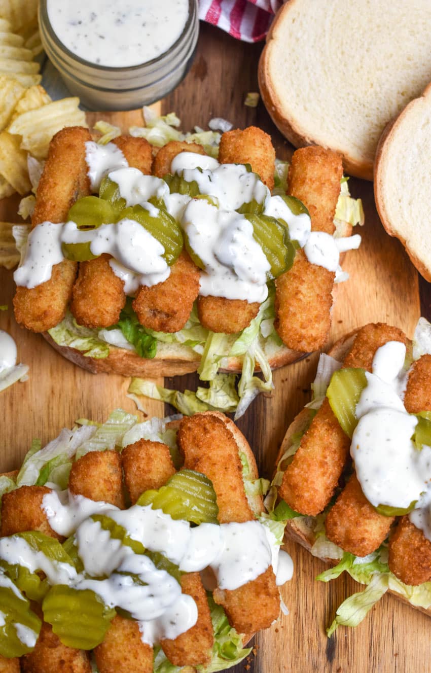 open face fish finger sandwiches on a wooden cutting board