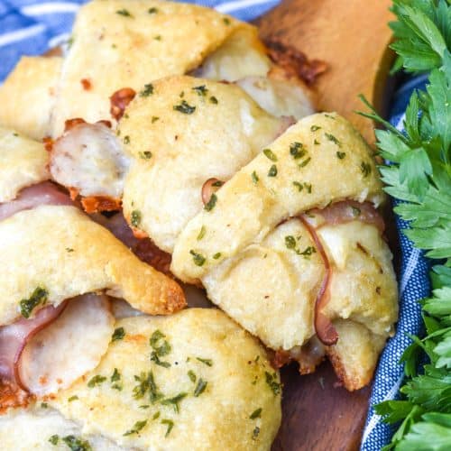 ham and cheese crescent rolls arranged on a wooden cutting board