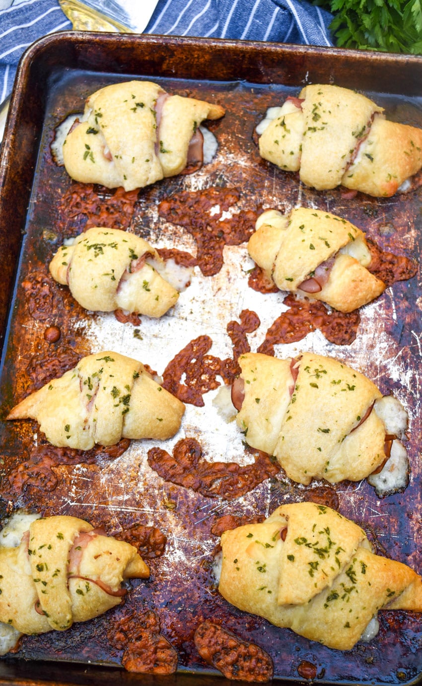 ham and swiss crescent rolls on a metal baking sheet