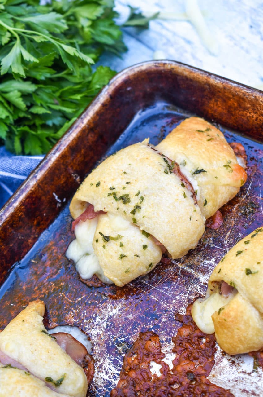 ham and swiss crescent rolls on a metal baking sheet