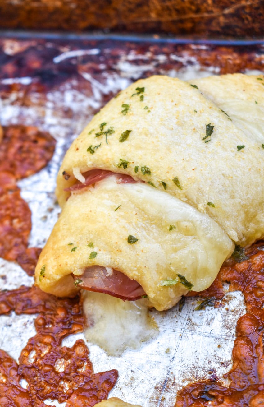 a close up of ham and cheese crescent rolls on a metal baking sheet