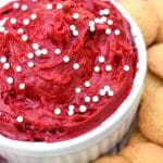 red velvet cake batter dip in a small white bowl surrounded by cookies