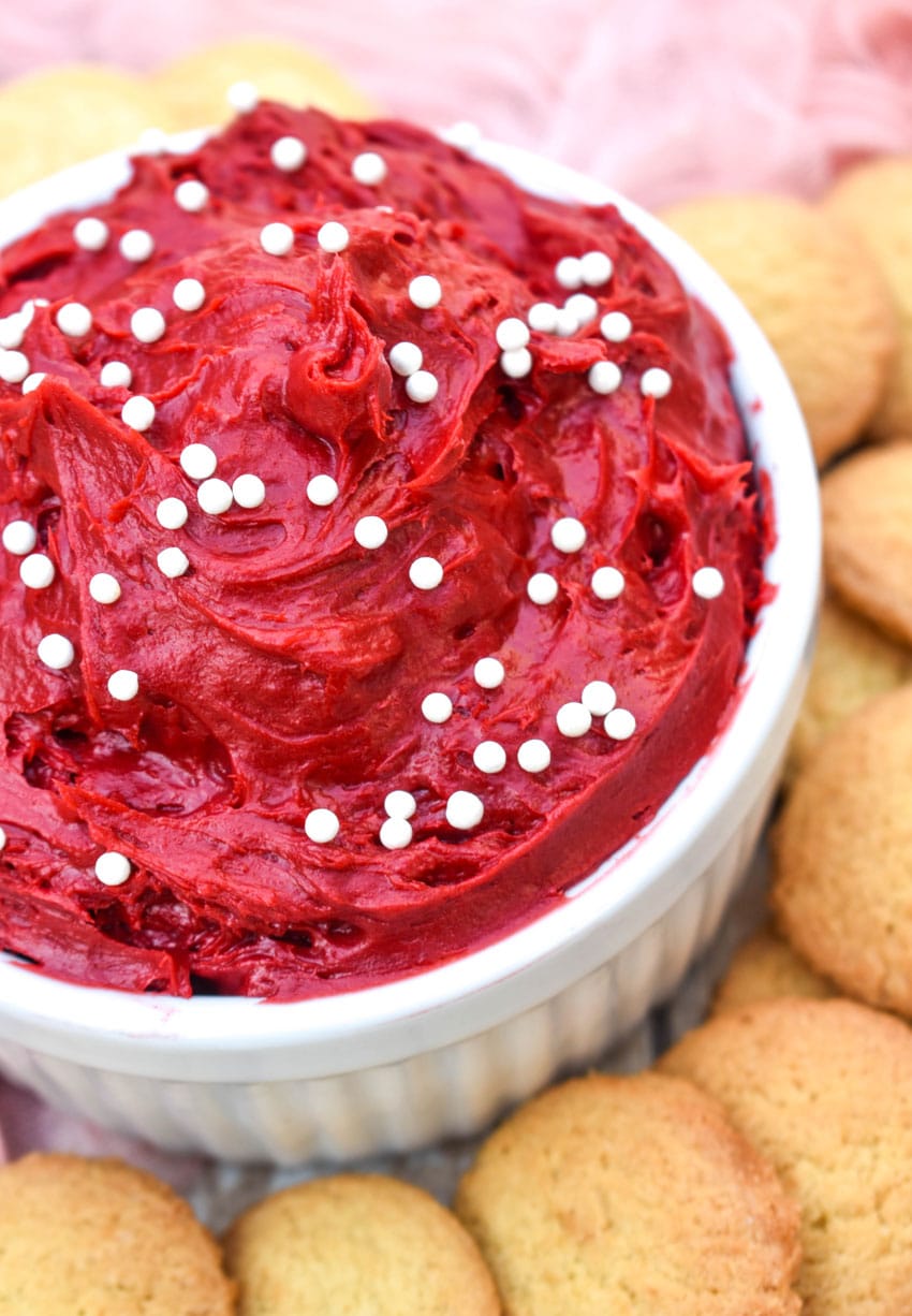 red velvet cake batter dip in a small white bowl surrounded by cookies