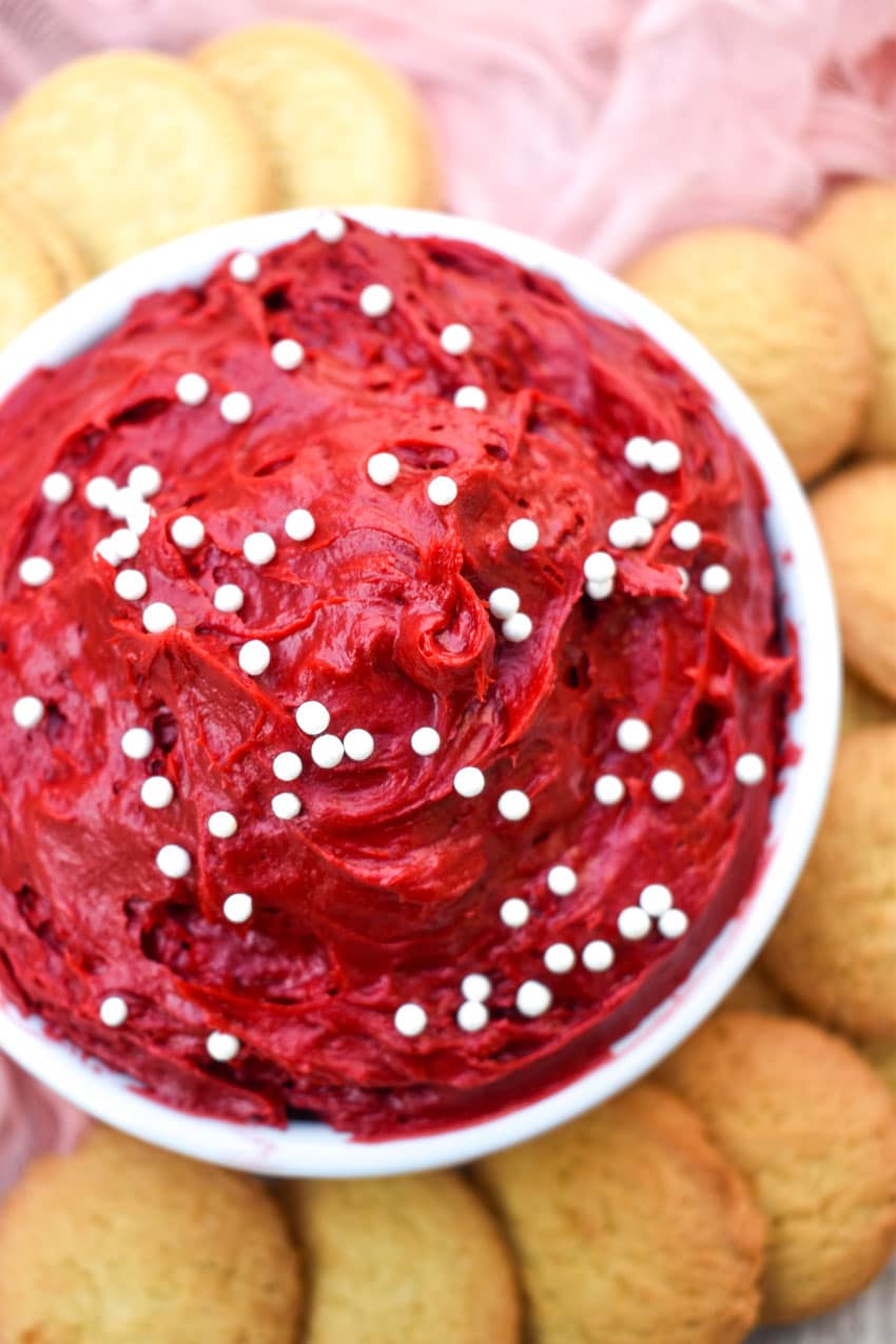 red velvet cake batter dip in a small white bowl surrounded by cookies