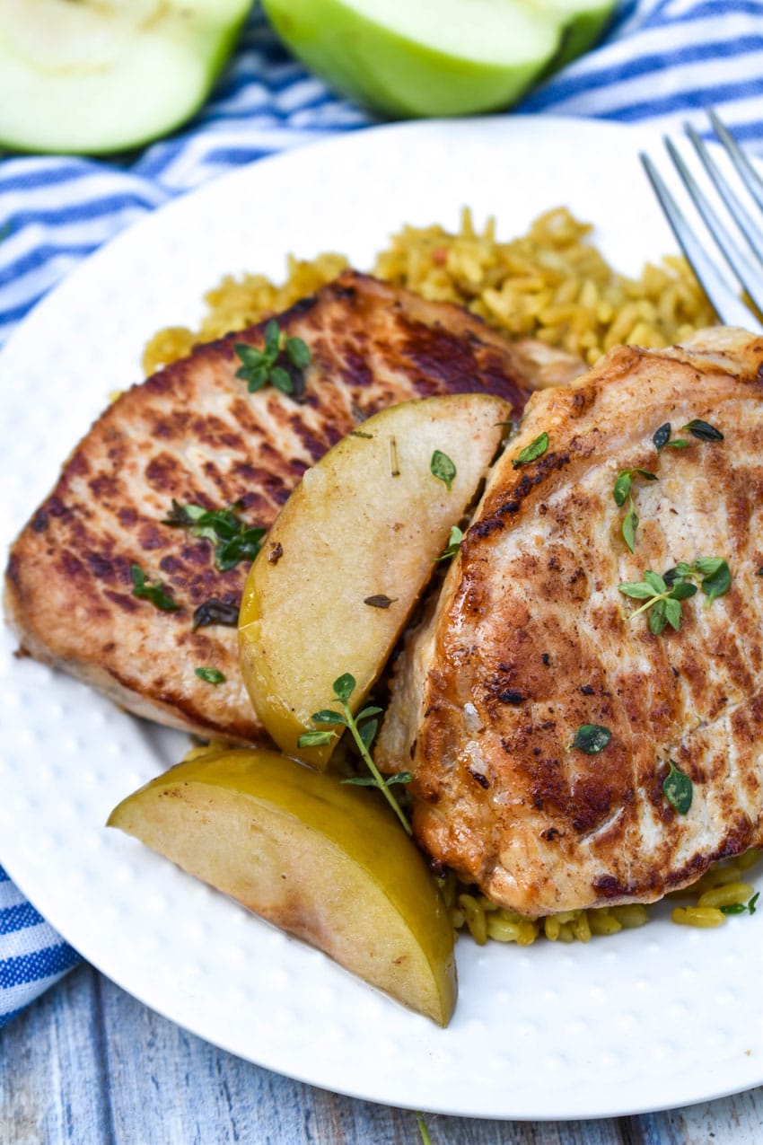 slow cooker pork chops and apples on a small white plate with a silver fork resting on the side
