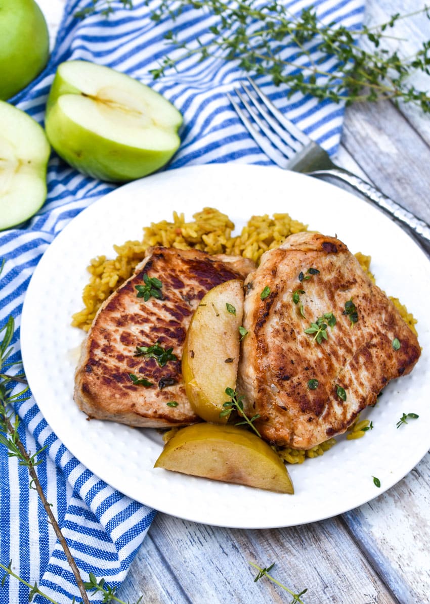 slow cooker pork chops and apples on a small white plate with a silver fork resting on the side