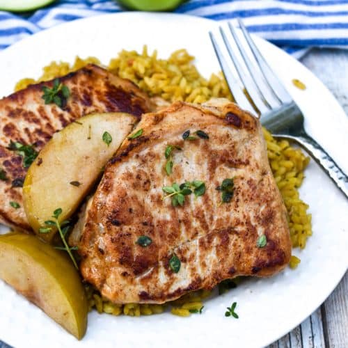 slow cooker pork chops and apples on a small white plate with a silver fork resting on the side
