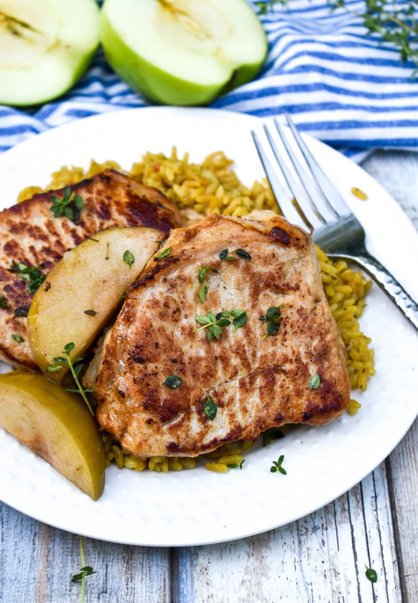 slow cooker pork chops and apples on a small white plate with a silver fork resting on the side
