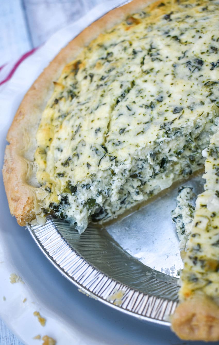 a sliced creamed spinach pie in a white pie plate