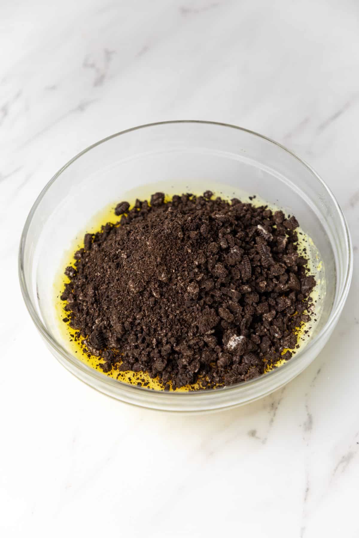crushed oreos being added to a bowl of instant vanilla pudding