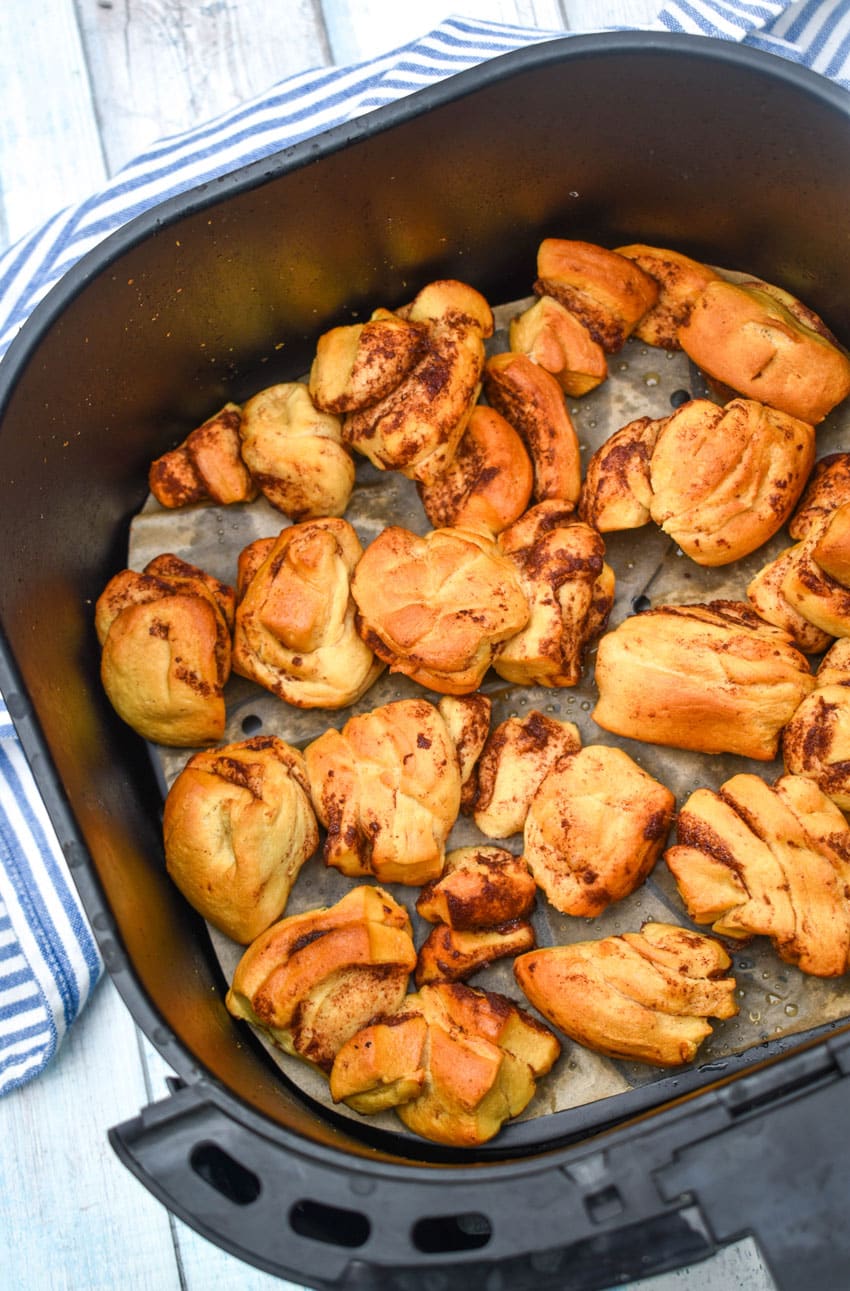 baked cinnamon roll pieces in the basket of an air fryer