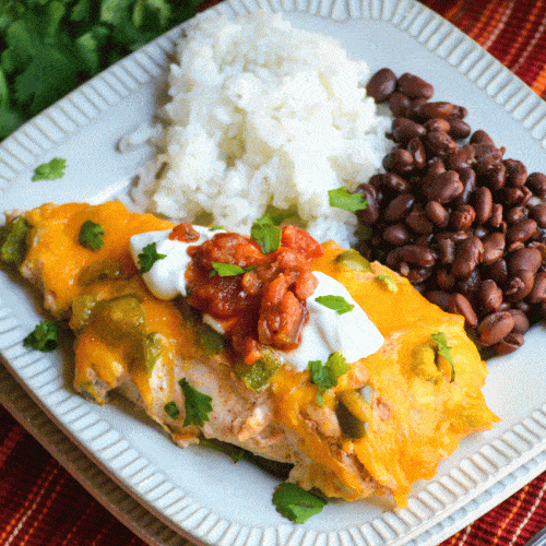 baked cheesy fajita chicken next to steamed white rice and black beans on a small square white plate