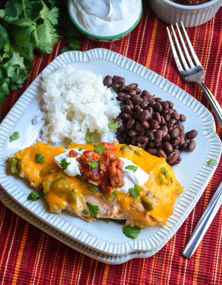 baked cheesy fajita chicken next to steamed white rice and black beans on a small square white plate