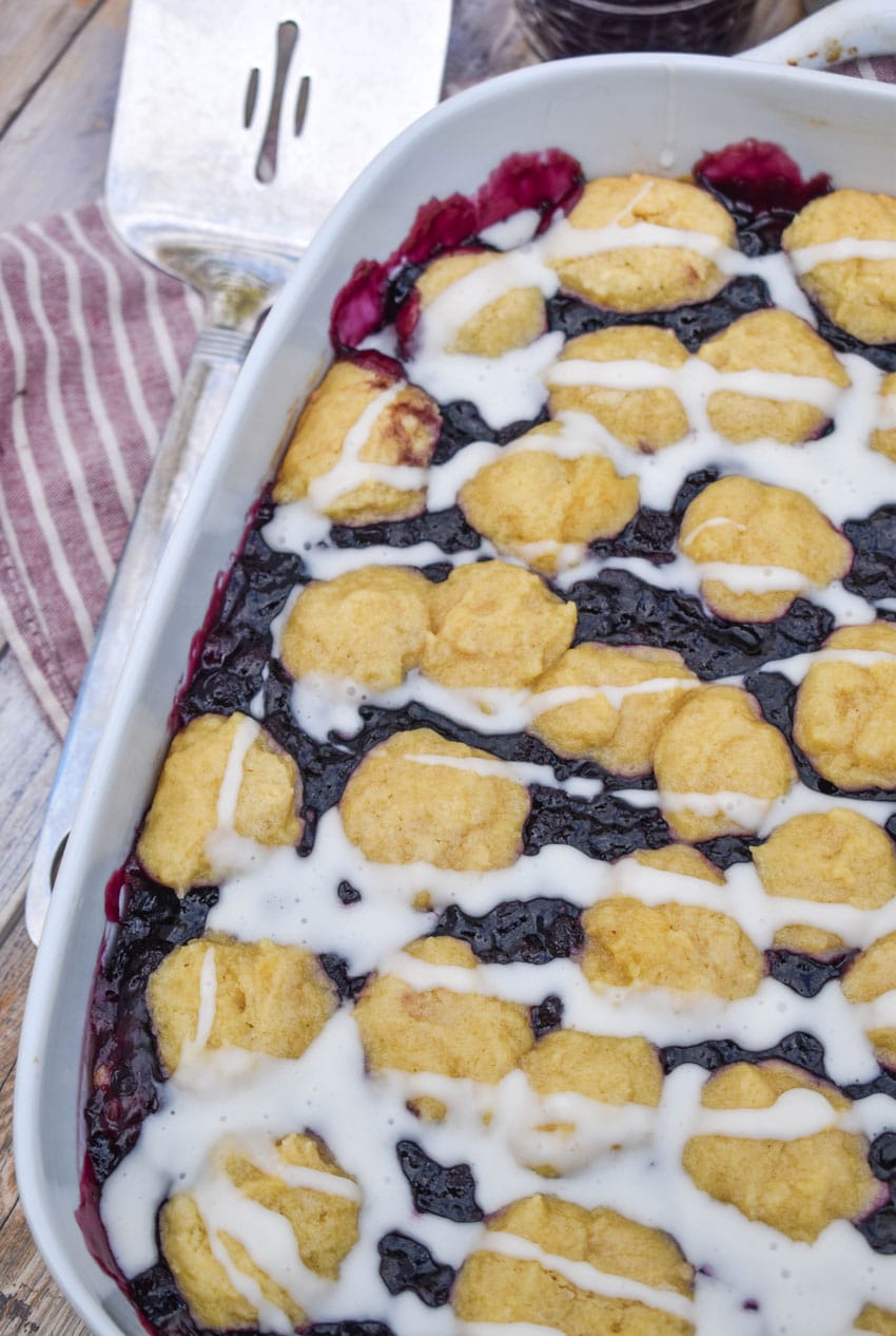blueberry pie bars drizzled with powdered sugar glaze in a white baking dish
