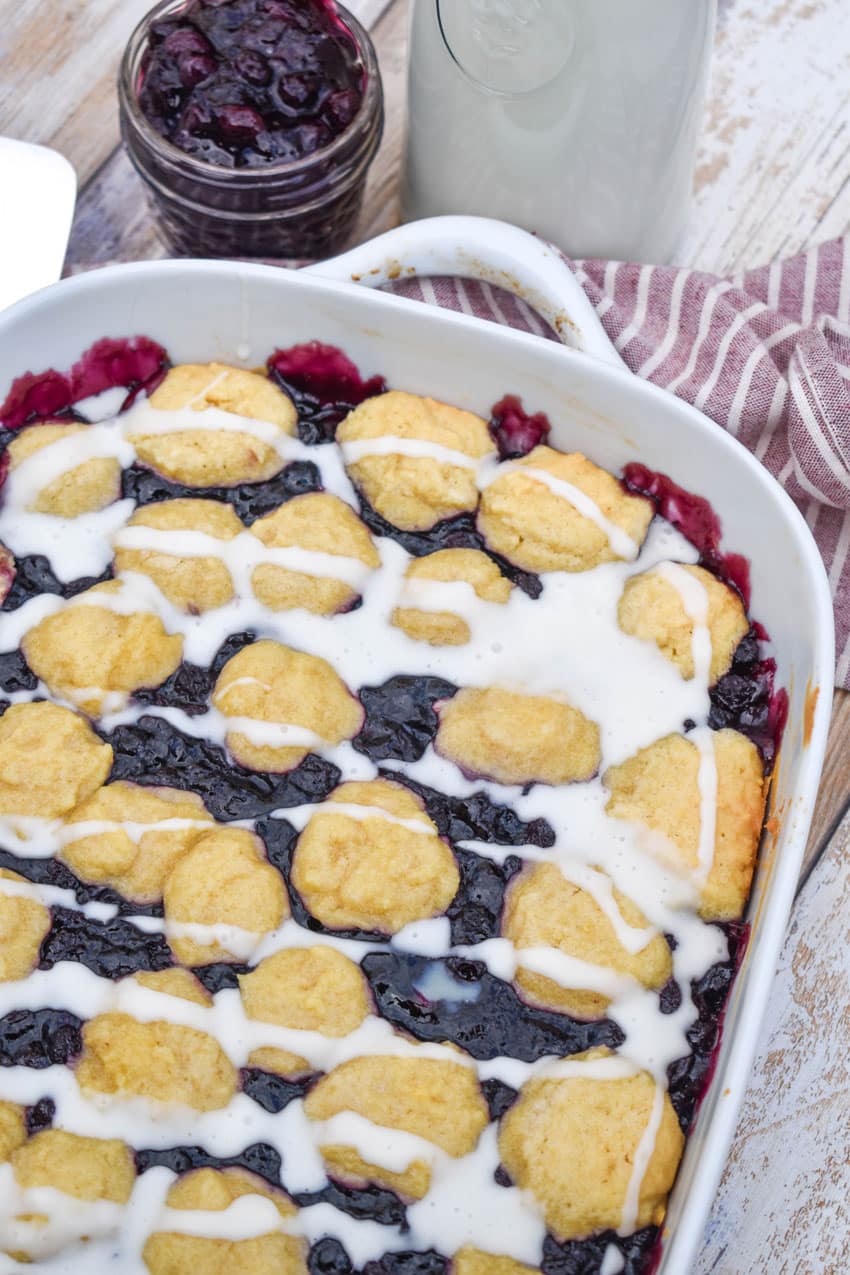 blueberry pie bars drizzled with powdered sugar glaze in a white baking dish