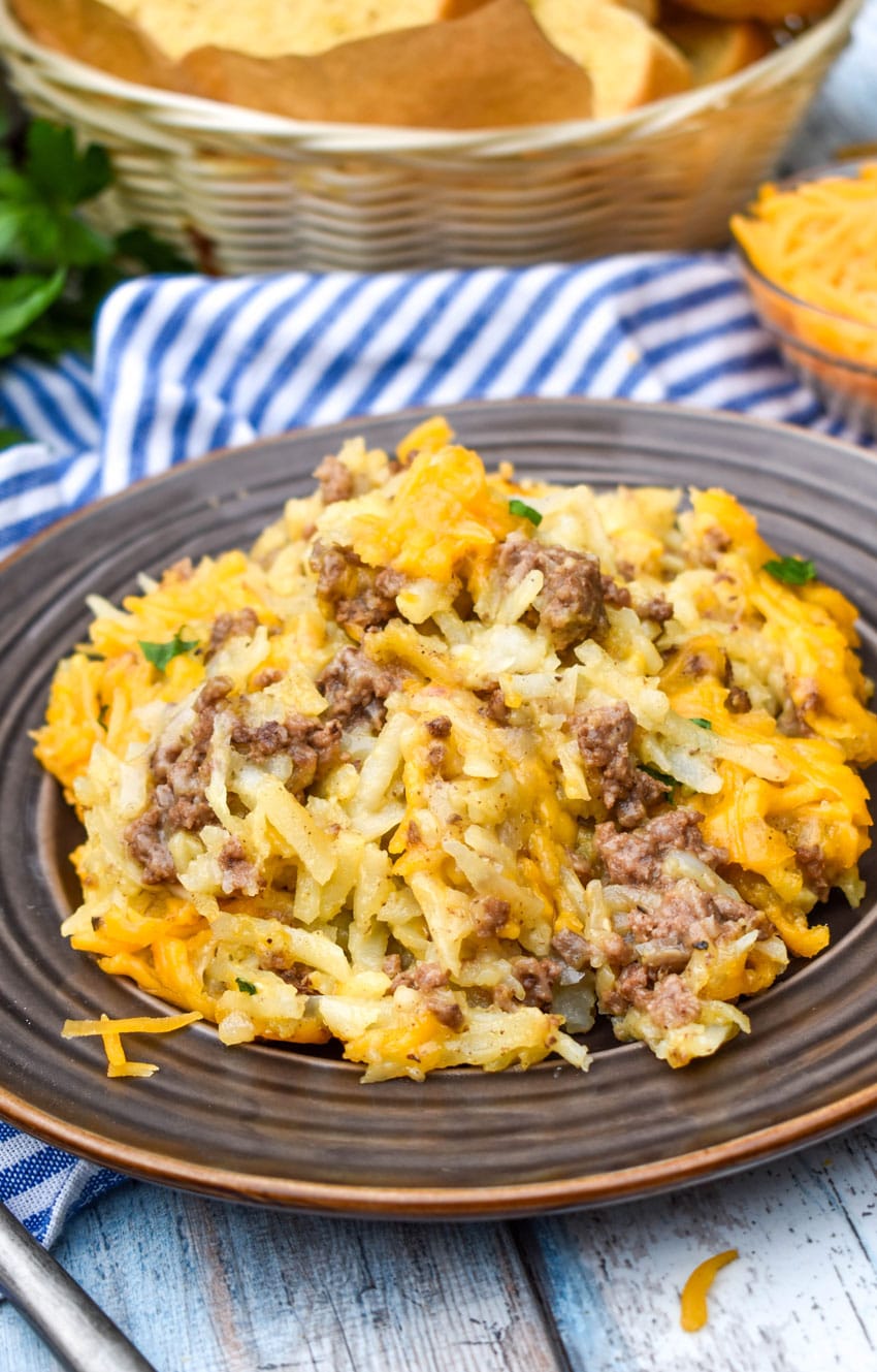 cheesy hashbrown casserole with ground beef on a brown plate with a fork resting on the side