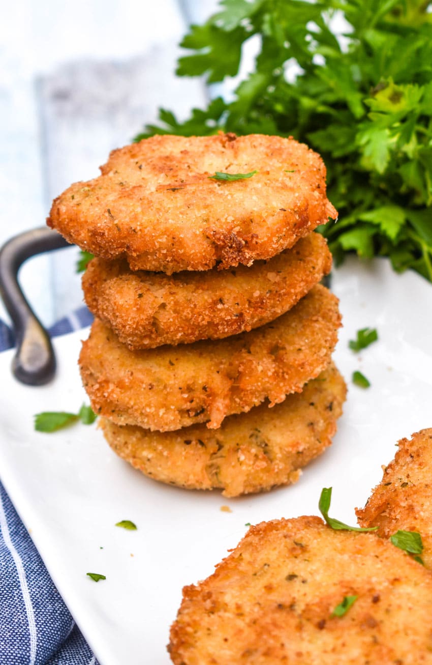 a stack of crispy chicken fritters on a white serving plate