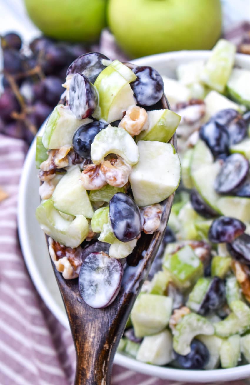 a wooden spoon holding up a scoop of waldorf salad