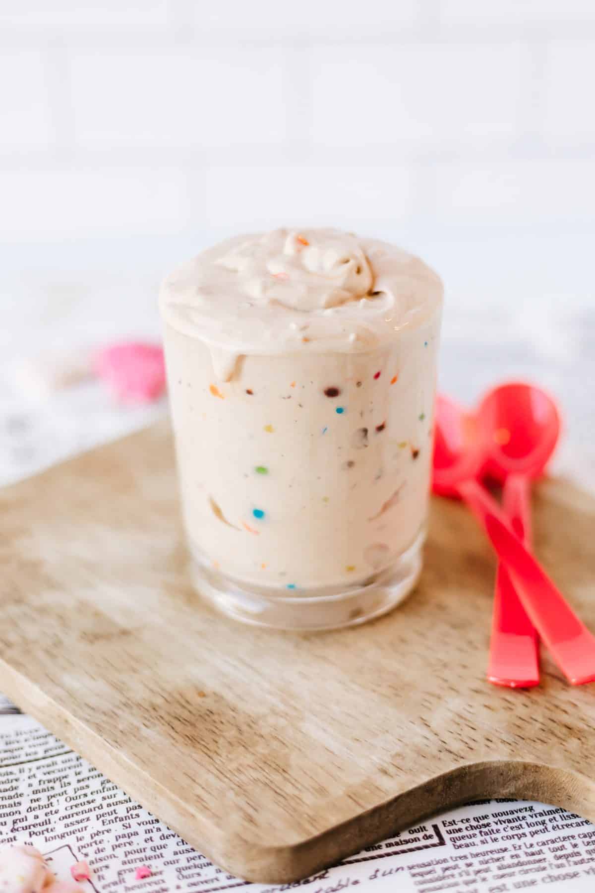 homemade m&m's blizzard in a glass jar sat on a wooden cuttin gboard