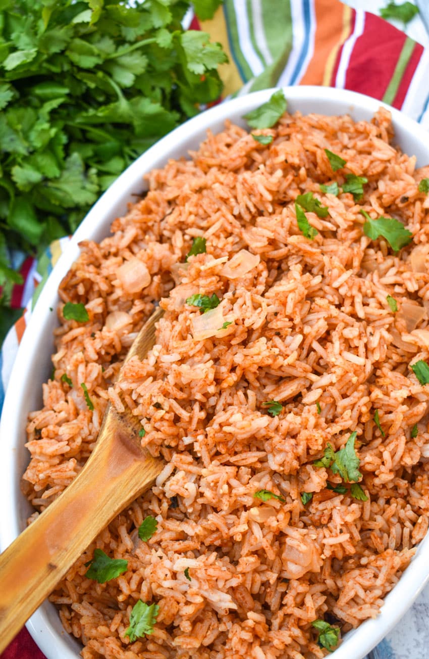 a wooden spoon scooping instant pot spanish rice out of a white serving dish