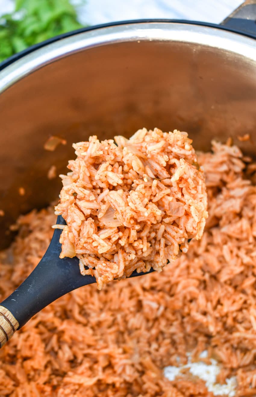 a wooden spoon holding up a scoop of instant pot spanish rice